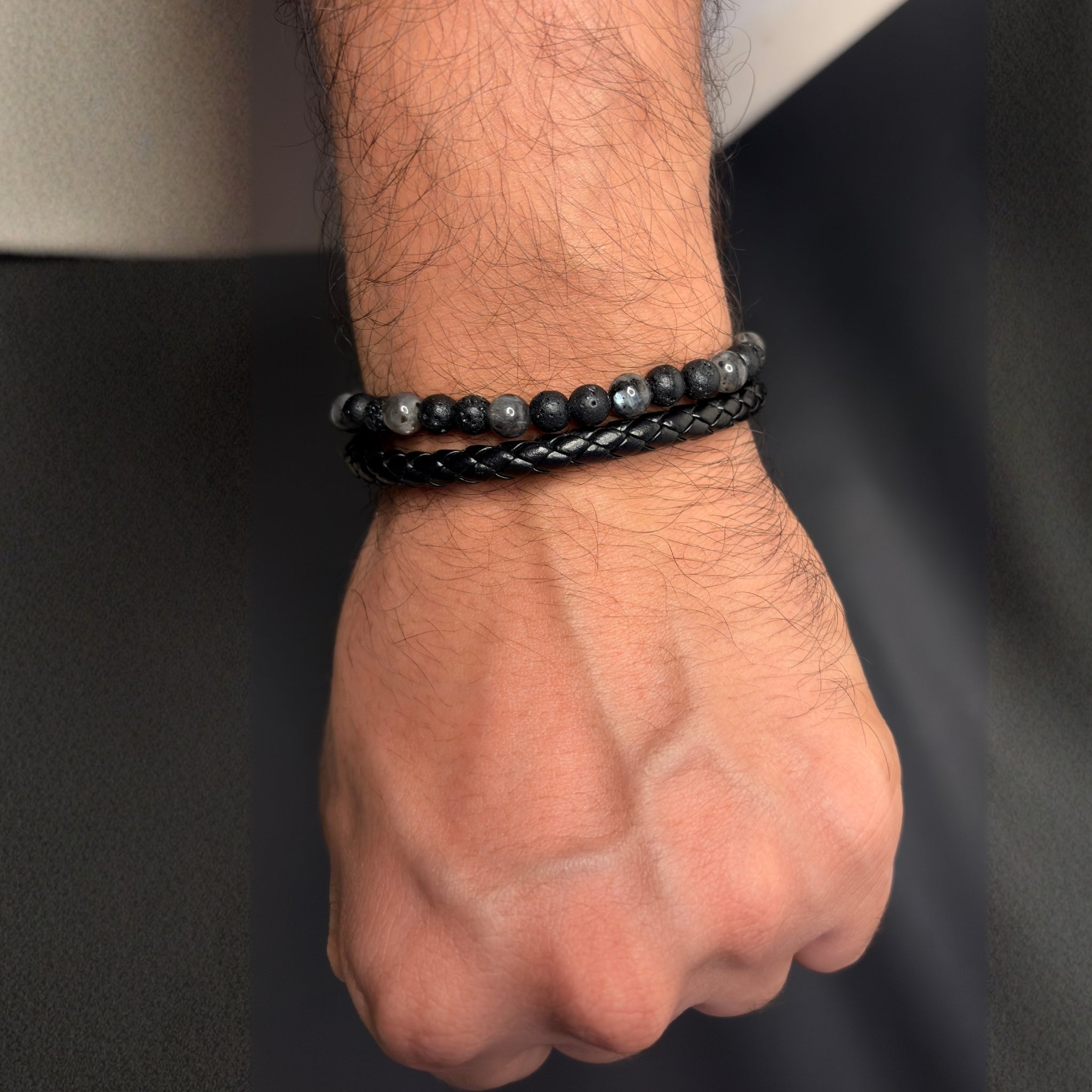 Close-up of a wrist wearing two black beaded bracelets against a dark background