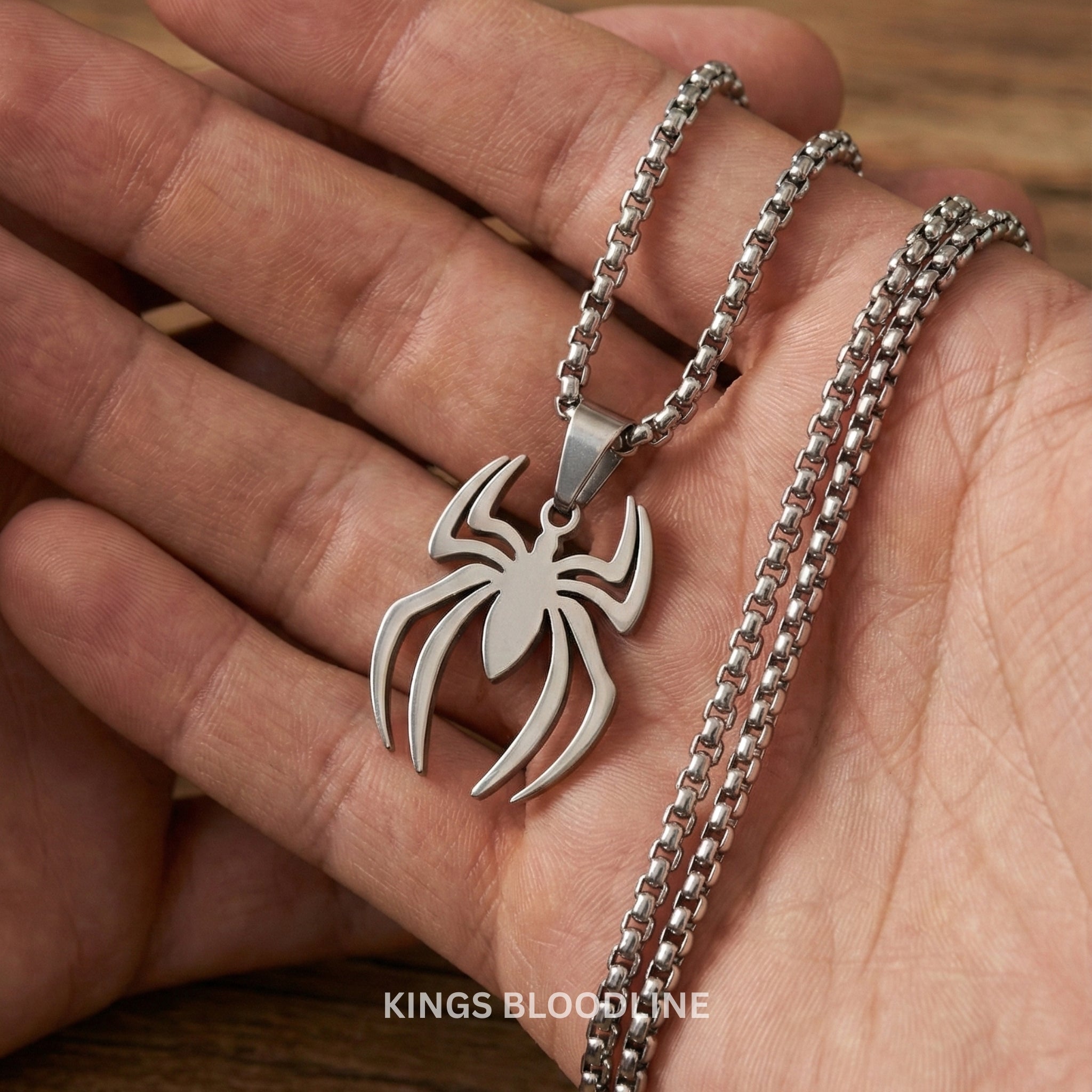 Silver spider pendant necklace on a hand with 'Kings Bloodline' branding.