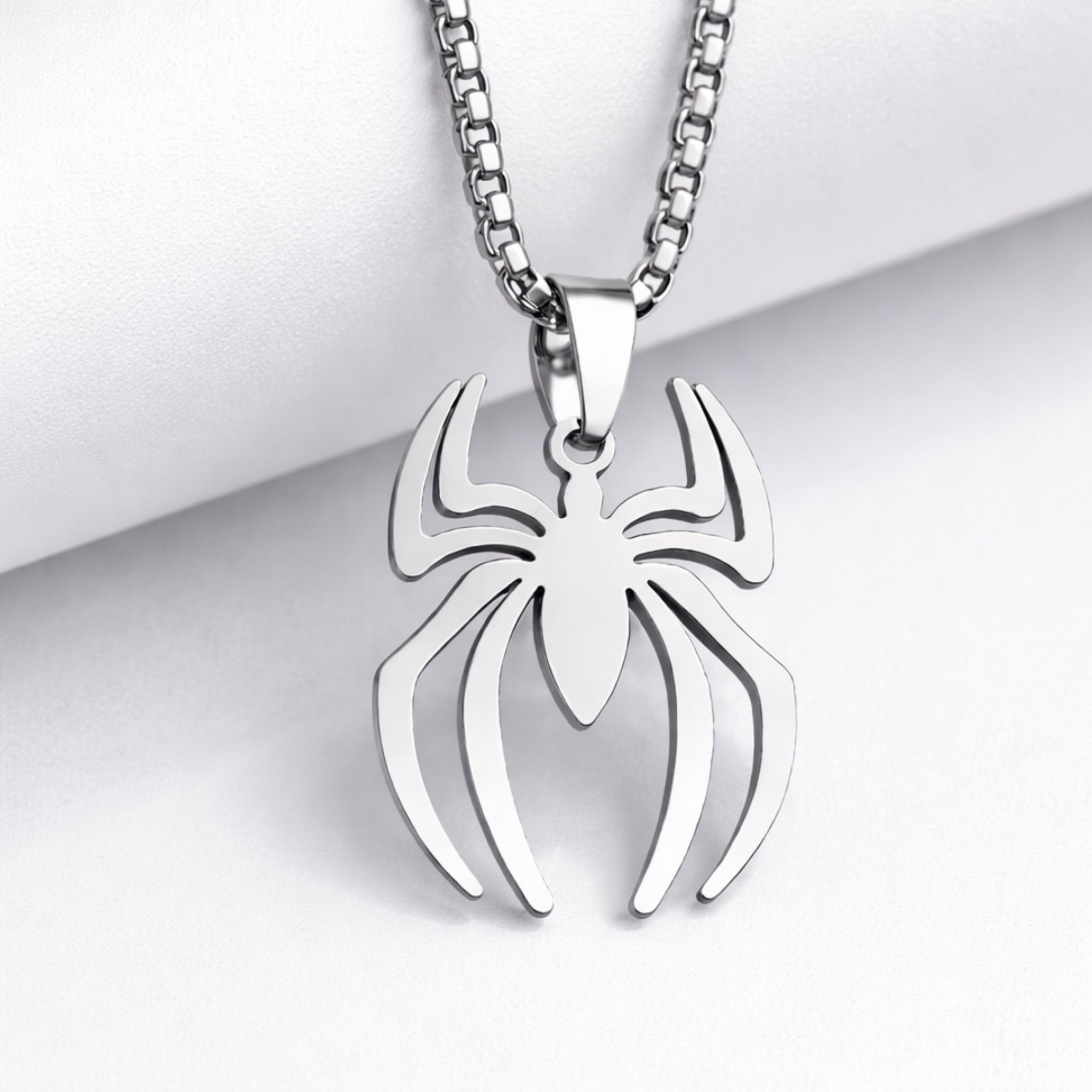 Spider-shaped pendant on a chain against a light background