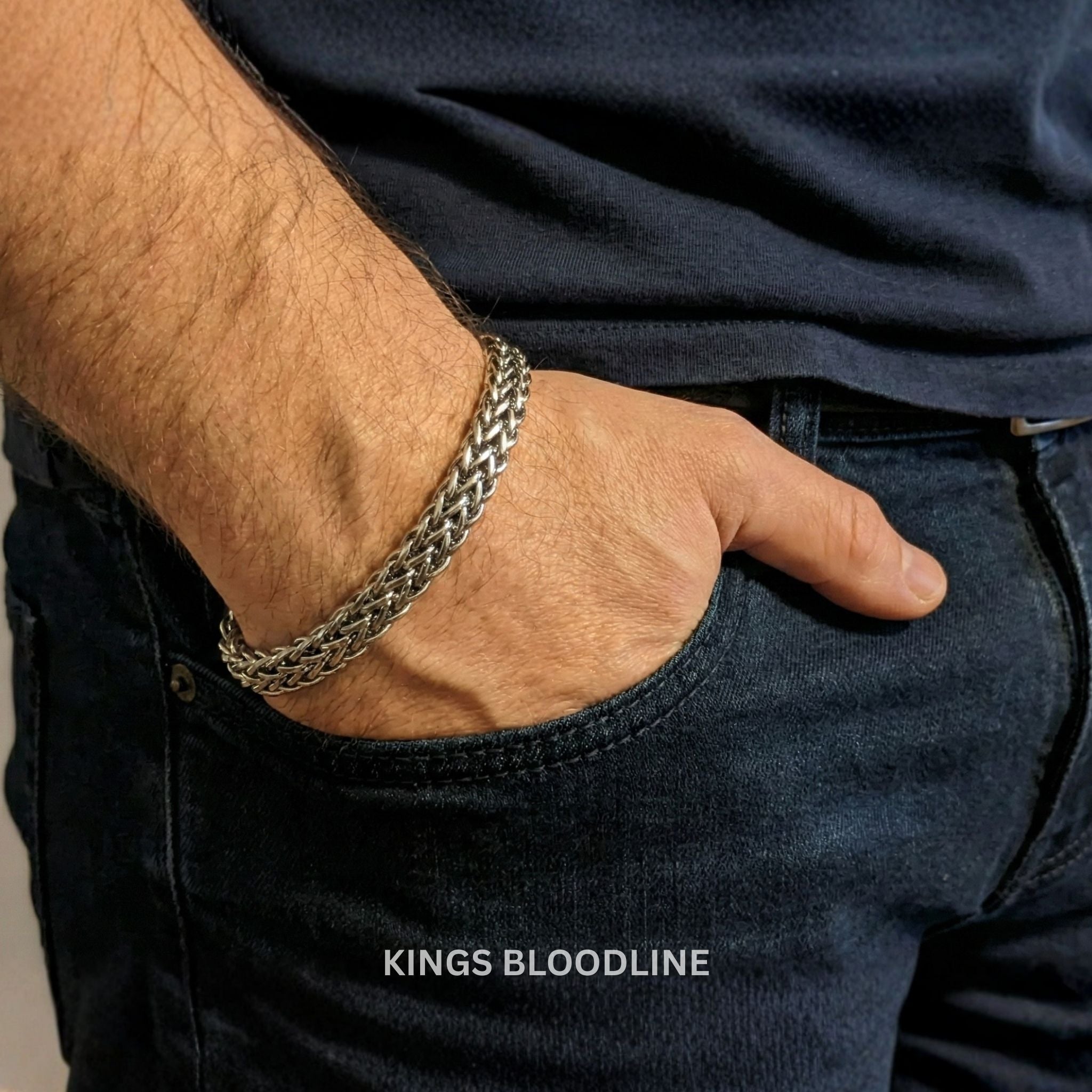 Close-up of a hand wearing a silver chain bracelet with 'KINGS BLOODLINE' branding.